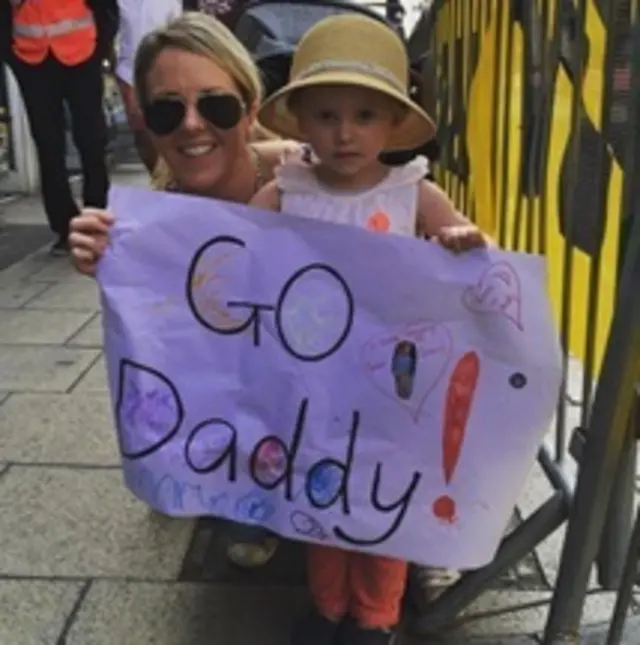 Kate Kerr with her little who is holding a sign that she has made that reads Go Daddy!