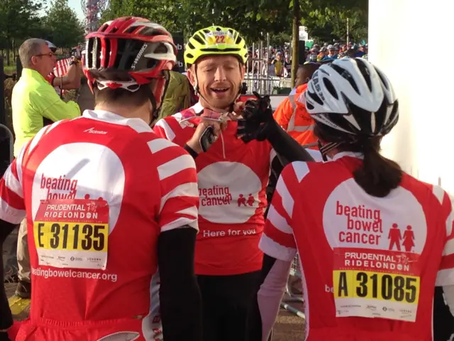 Matt Dawson fastens his cycle helmet with fellow cyclists looking on