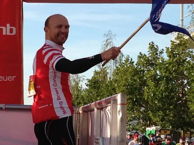 Matt Dawson in cycling gear waving a flag