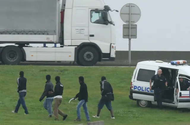 Migrants in Calais with police officer