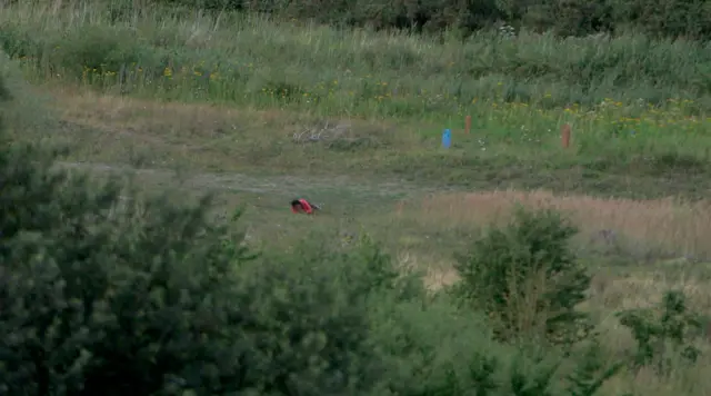 Woman rolls "sniper style" across a field near Eurostar railway tracks to avoid being seen by police