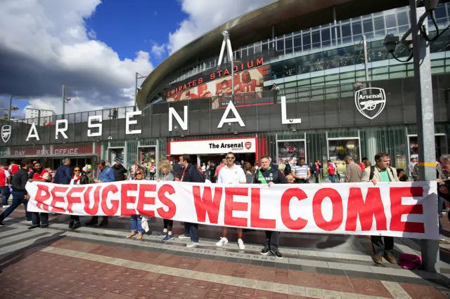 Arsenal fans hold a "Refugees welcome" banner outside Emirates Stadium