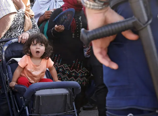 Hungarian police transfer migrants into buses at the Croatian-Hungarian border near Beremend, Hungary