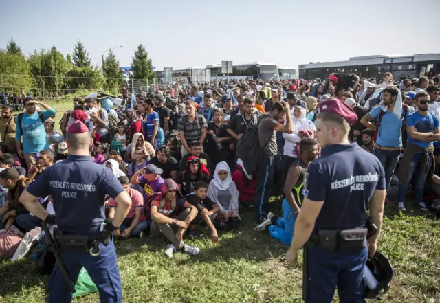 Hungarian policemen keep a close eye on a large group of migrants and refugees at border crossing between Hungary and Croatia