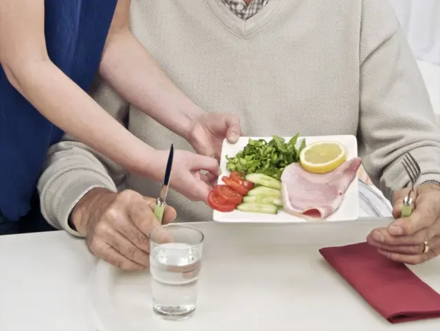 Care worker giving a man his lunch