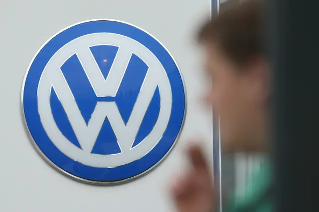 A young man smokes a cigarette as the logo of German carmaker Volkswagen