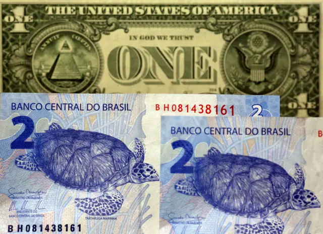 Two Brazilian real notes and one US dollar note