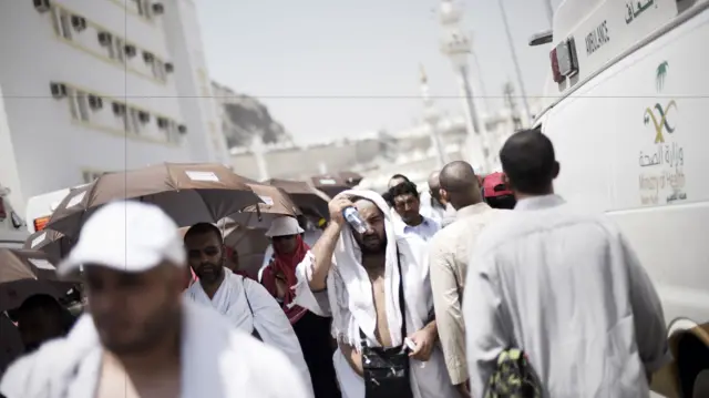 Pilgrims walk past ambulances