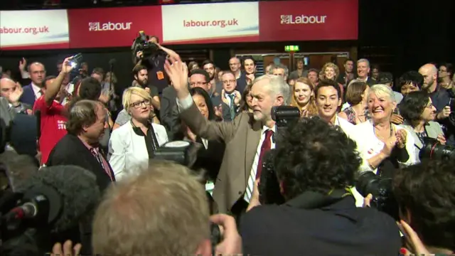 Jeremy Corbyn waves to supporters as he leaves the conference hall