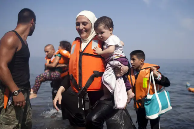 A Syrian refugee holds a child moments after arriving on a dinghy on the Greek island of Lesbos, September 3, 2015.