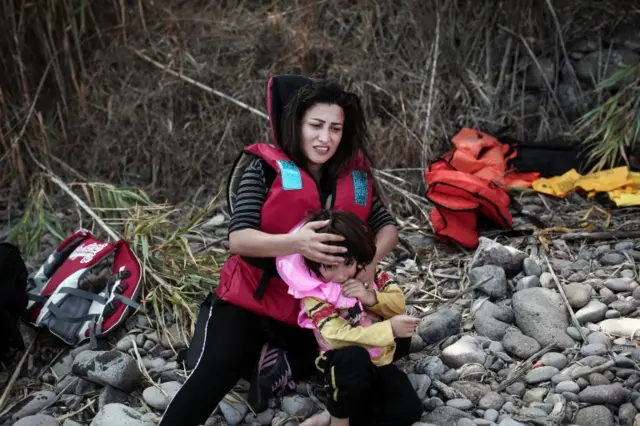 A refugee hugs her child after arriving on the Greek island Lesbos in an inflatable dingy from Turkey on September 3, 2015.