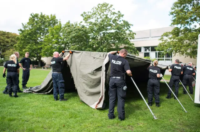 Police officers set up a tent for refugees during the day, in the grounds of Lower Saxony central police headquarters in Hanover, Germany, 03 September 2015.