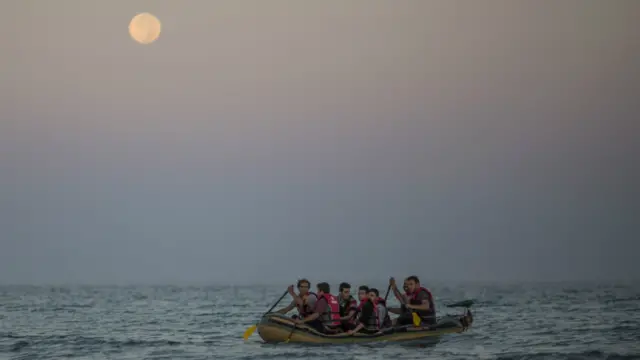 Migrant families arrive in an inflatable dinghy on the beach at sunrise in Kos, Greece - 30 August 2015