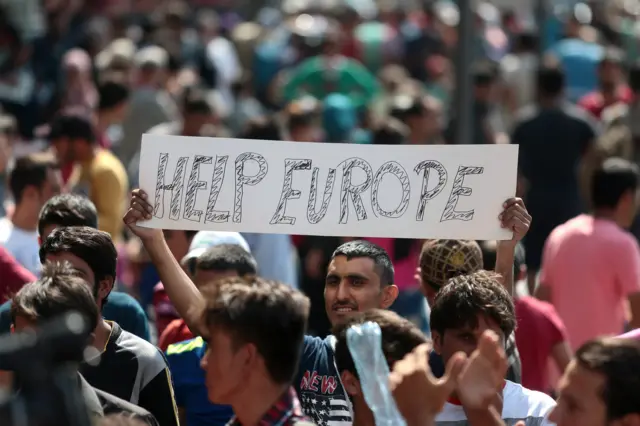 A man holds a placard reading 'Help Europe' outside the Keleti (East) railway station in Budapest