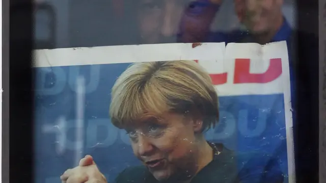 A migrant holds up a newspaper showing German Chancellor Angela Merkel after his arrival from Austria at Munich Hauptbahnhof main railway station