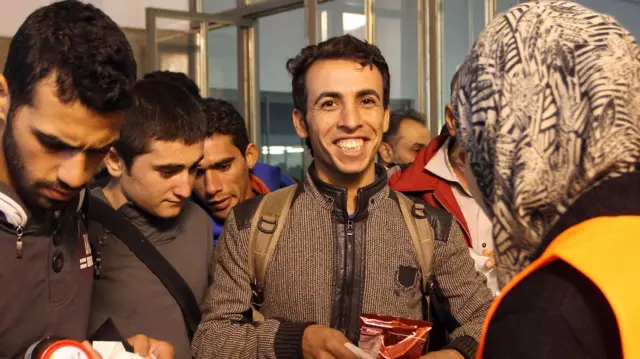 Migrants receive food from volunteers after their arrival from Salzburg in Austria