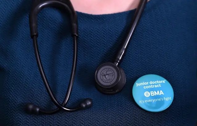 A doctor wearing a badge next to her stethoscope