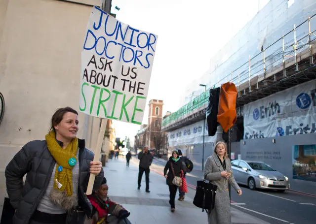 A junior doctor holding a sign