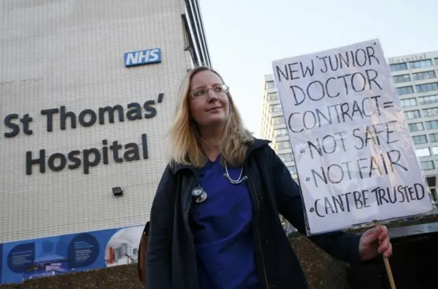 A doctor holds a placard during a strike outside St Thomas" hospital in central London