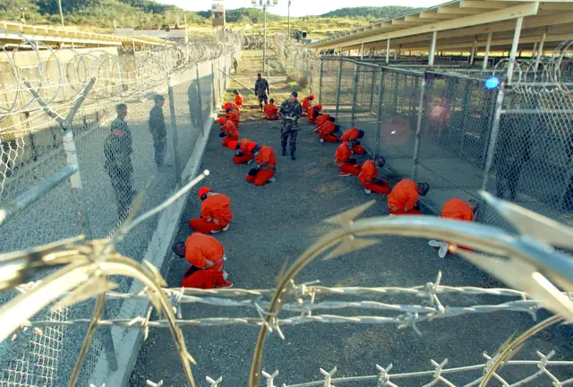 U.S. Military Police guard Taliban and al Qaeda detainees in orange jumpsuits