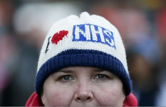 A woman wears a hat that reads "I Love NHS" during a strike outside St Thomas" hospital in central London