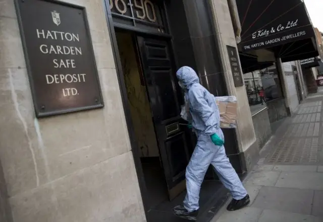 A police forensic officer enters a safe deposit building on Hatton Garde