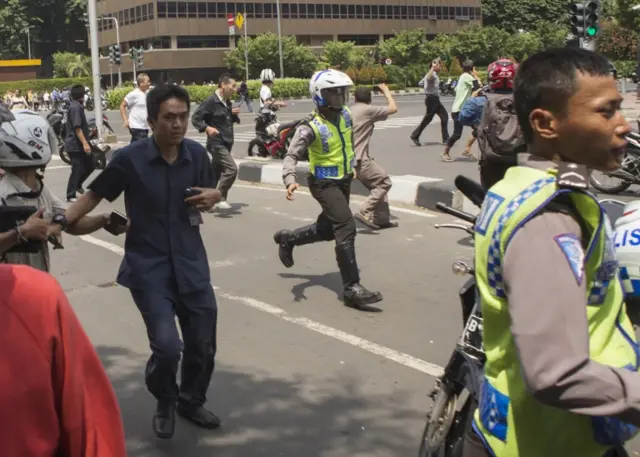 People, including unarmed police officers, flee from the scene after a gun battle broke out following an explosion in Jakarta, Indonesia (14 Jan. 2016)