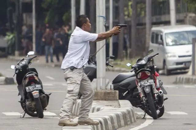 A plainclothes police officer aims his gun at attackers