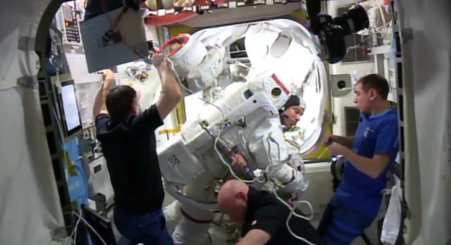 Crew members help Tim Kopra out of his helmet