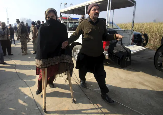 A teacher walks with a pair of crutches following her rescue after a group of militants stormed the Bacha Khan University in Charsadda