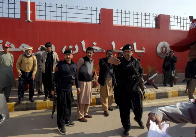 Pakistani police officers clear the way for an ambulance to arrive at Bacha Khan University in Charsadda town