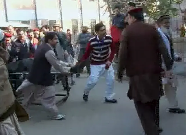 People carry a casualty in a militant attack at Bacha Khan University, on a stretcher in Charsadda