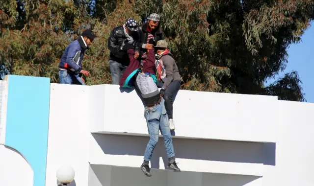 Man handing on to building in Kasserine