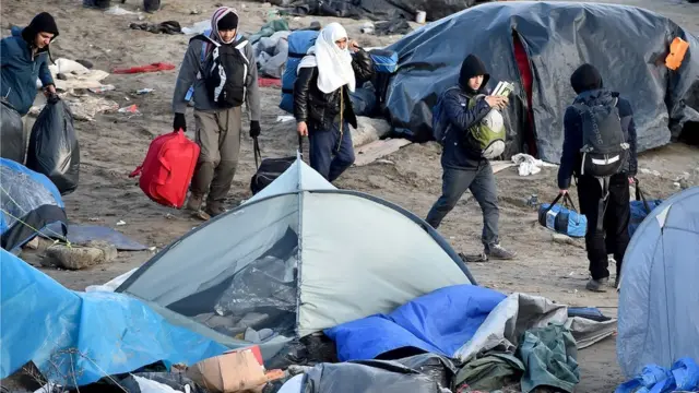 Migrants and volunteers clear part of the camp known as the Jungle