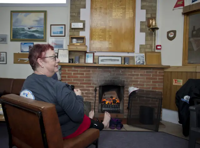 Jo warms her feet on a fire