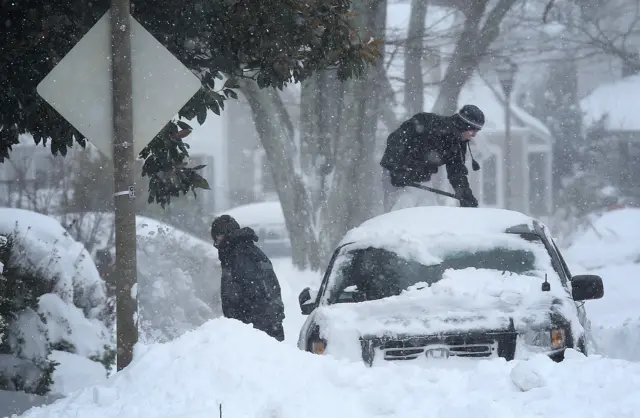 Residents clear snow from their car during a heavy snow fall in Arlington, Virginia