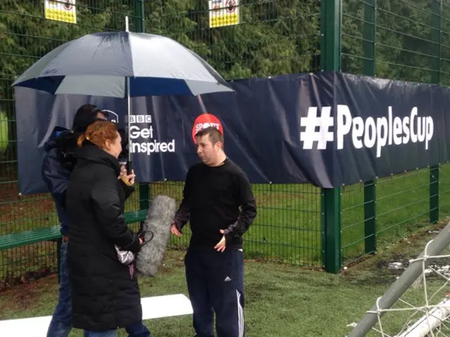 crew interviewing man by football pitch