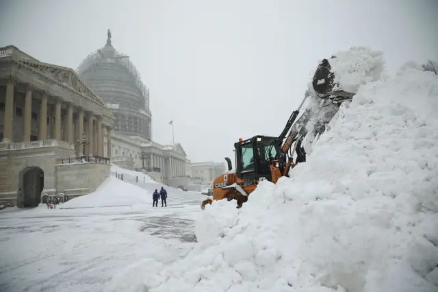 A bulldozer clears snow in front the US Capitol, DC