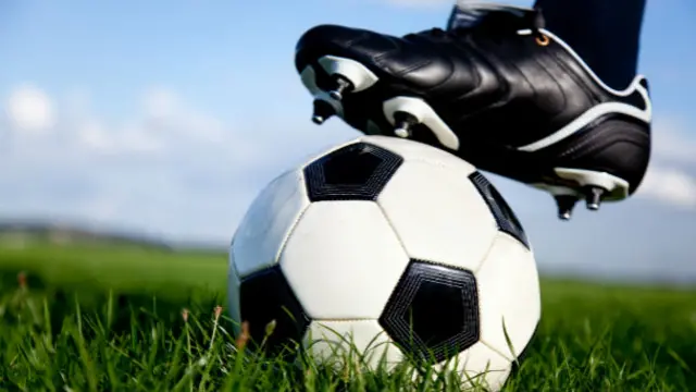 close up of a football being held down by a football boot