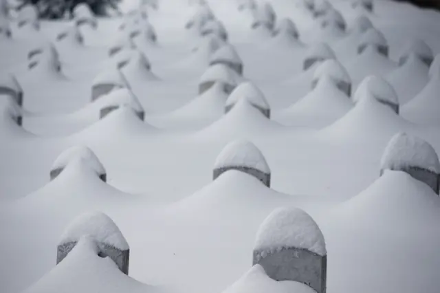 Headstones are nearly covered by snow at Arlington National Cemetery