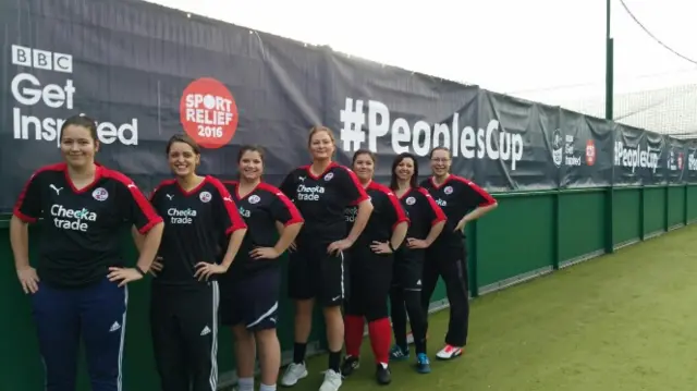 Line of female football players against People's Cup banner