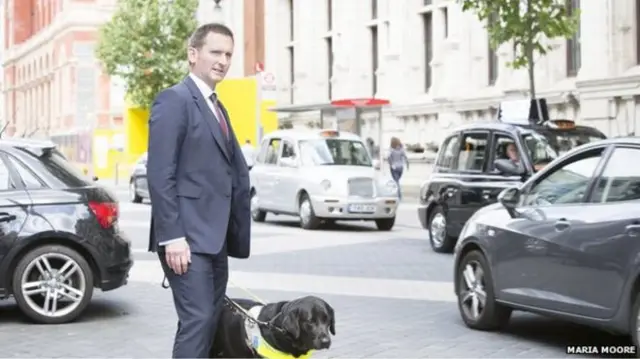 Lord Holmes and guide dog next to busy street