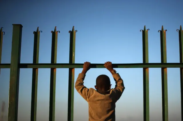 A youth watches children playing football in Alexandra township on July 1, 2013 in Johannesburg, South Africa