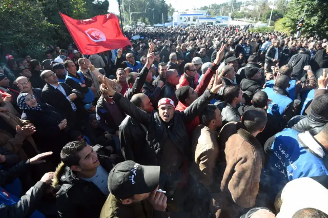 Tunisian policemen wave the national flag and shout slogans during a demonstration outside Tunis" Carthage Palace on January 25, 2016