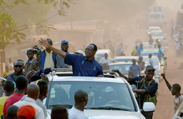Central African presidential candidate Anicet Georges Dologuele waves from a car in a motorcarde during a presidential campaign tour in Bangui on December 28, 2015
