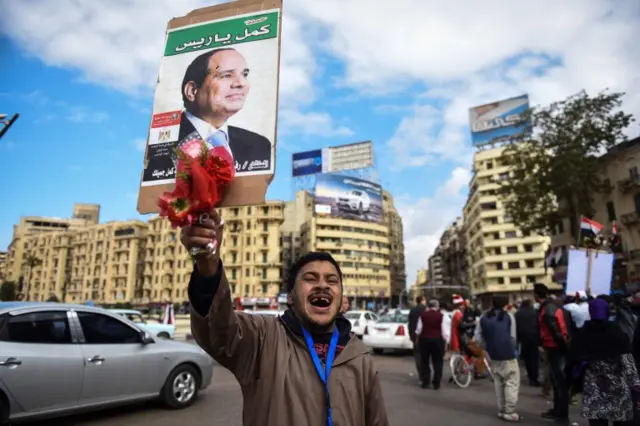 An man holds up a portrait of the Egyptian president on Cairo's landmark Tahrir Square on January 25, 2016