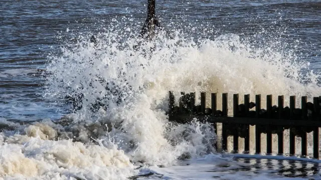 Crashing waves on a groyne, with a calm sea