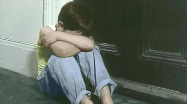 Young boy in doorway with head in his hands