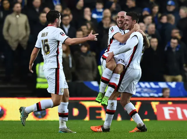 MK Dons" Irish midfielder Darren Potter (R) celebrates with MK Dons" English midfielder Samir Carruthers and MK Dons" Welsh defender Joe Walsh (L) after scoring their first goal during the English FA Cup fourth round football match between MK Dons and Chelsea at Stadium MK