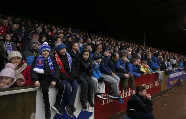 Young Carlisle United fans sit on the advertising boards during the Emirates FA Cup, fourth round match at Brunton Park